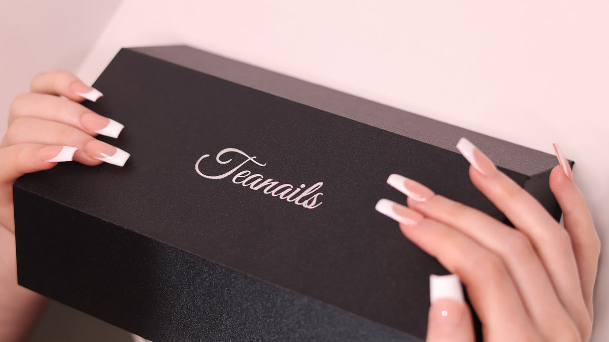 Hands with French-tip nails holding the branded Teanails box